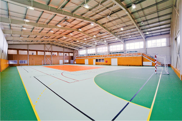 A frame-type steel structure of the sport hall with an inner tribune for watchers and with a connecting corridor to the basic school building.